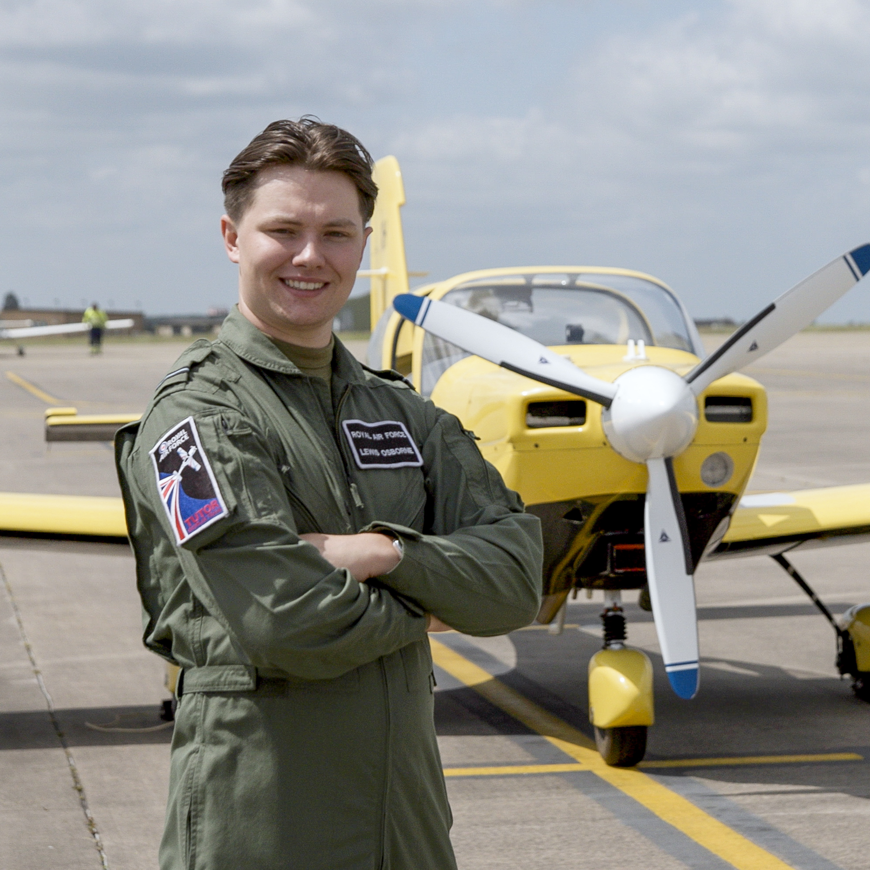 Flying Officer Osbourne in front of a yellow light aircraft